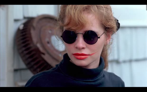 Hal Hartley - The Unbelievable Truth (1989), blonde in black john lennon round glasses with smear of lipstick on one side of face, looking like batman's joker