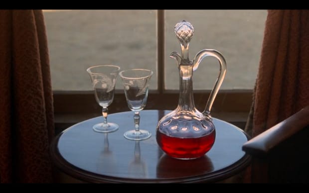 Terrence Malick - Days of Heaven (1978), decanter with red liquid and two glasses on a side table infront of a window