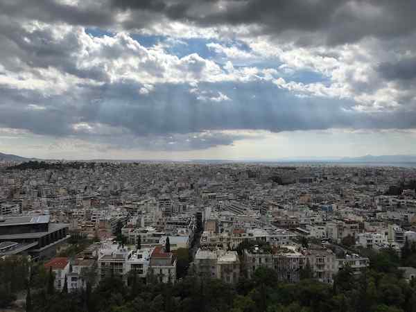 2020 photo from Athens showing cityscape and light shining through clouds, I think pictured from Acropolis