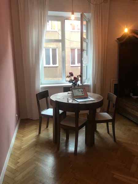 Photo of my kitchen showing millenial pink wall, pink screen of my open laptop, and some pink flowers in a bouquet on wooden table