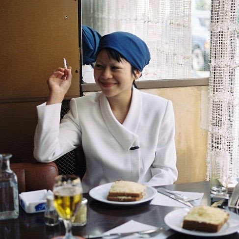 bernadette van huy sitting with sandwich in head wrap and white top