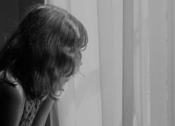 Screenshot of a woman's head looking out a window shown from behind, from Le 15/8