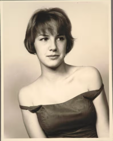 Sepia portrait of a young woman with short hair and an off-the-shoulder top, a young Eve Babitz