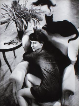 B&W photo of a woman lying on a sofa with black cats around, from Sybilla's FW 1988-1989 campaign