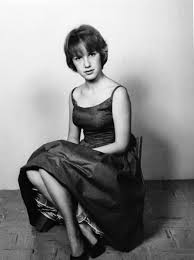 A woman in a party dress sitting in a chair, a young Eve Babitz