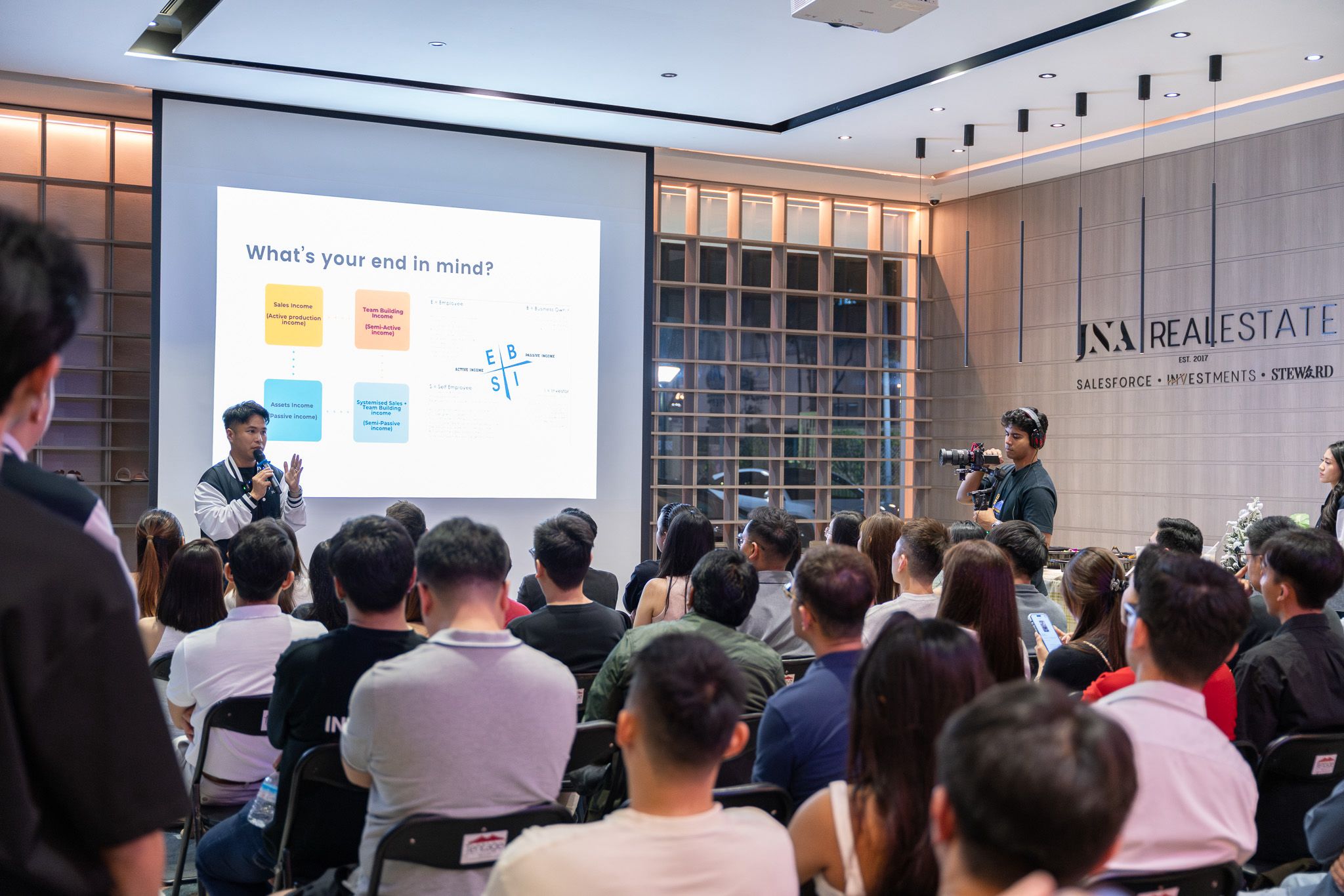 Junese presenting to large audience at JNA