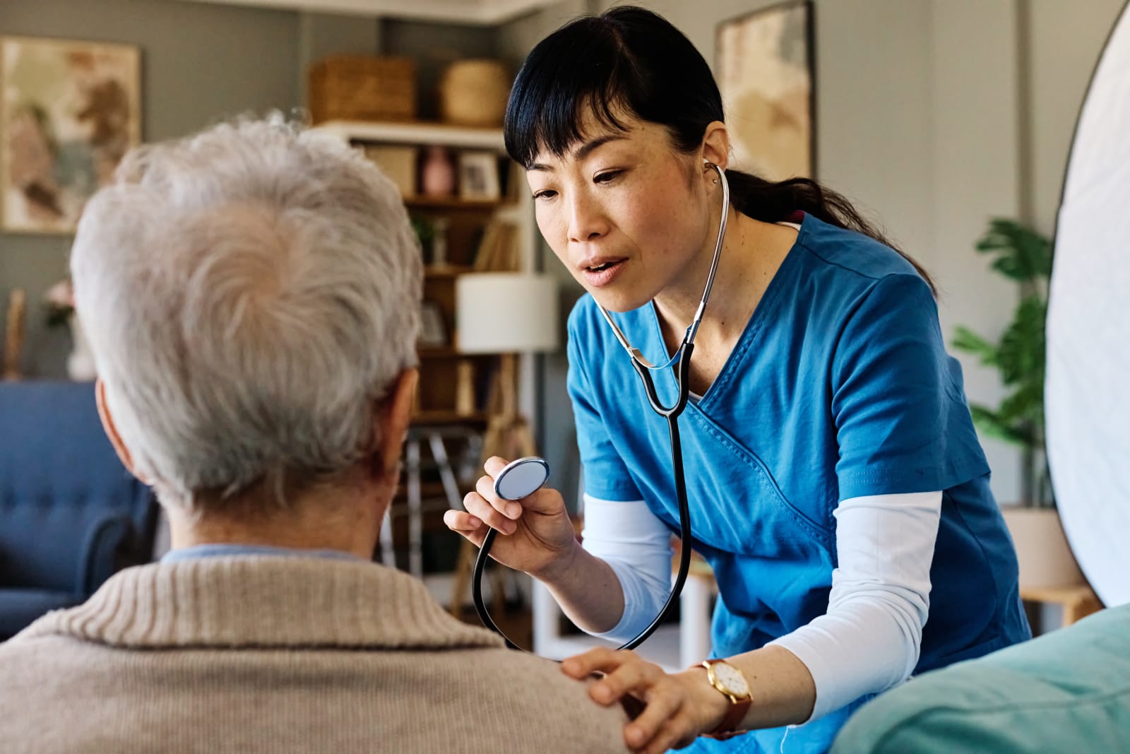 Caregiver speaking warmly with an elderly woman during a medication check-in at home