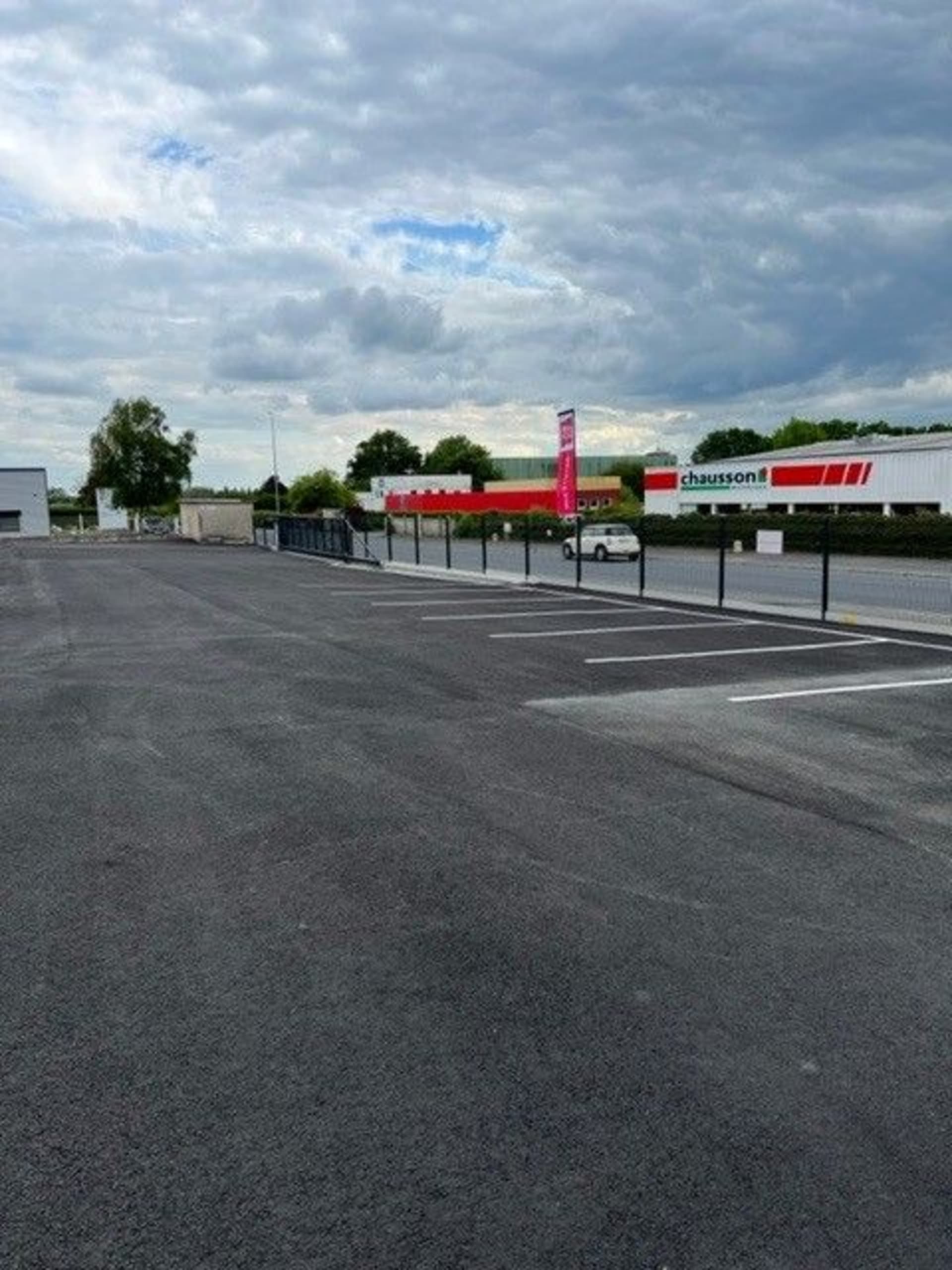 Parking goudronné vide à proximité d'une enseigne Chausson, HOMEBOX Saint-Lô, 377 Rue Léon Jouhaux à Saint-Lô