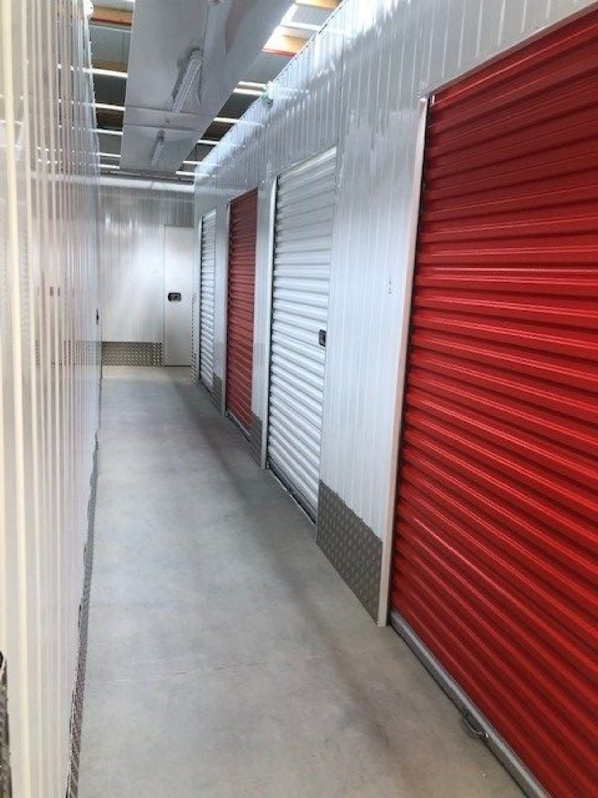 Couloir intérieur avec portes de boxes rouges et blanches en perspective du centre HOMEBOX Lorient Quéven