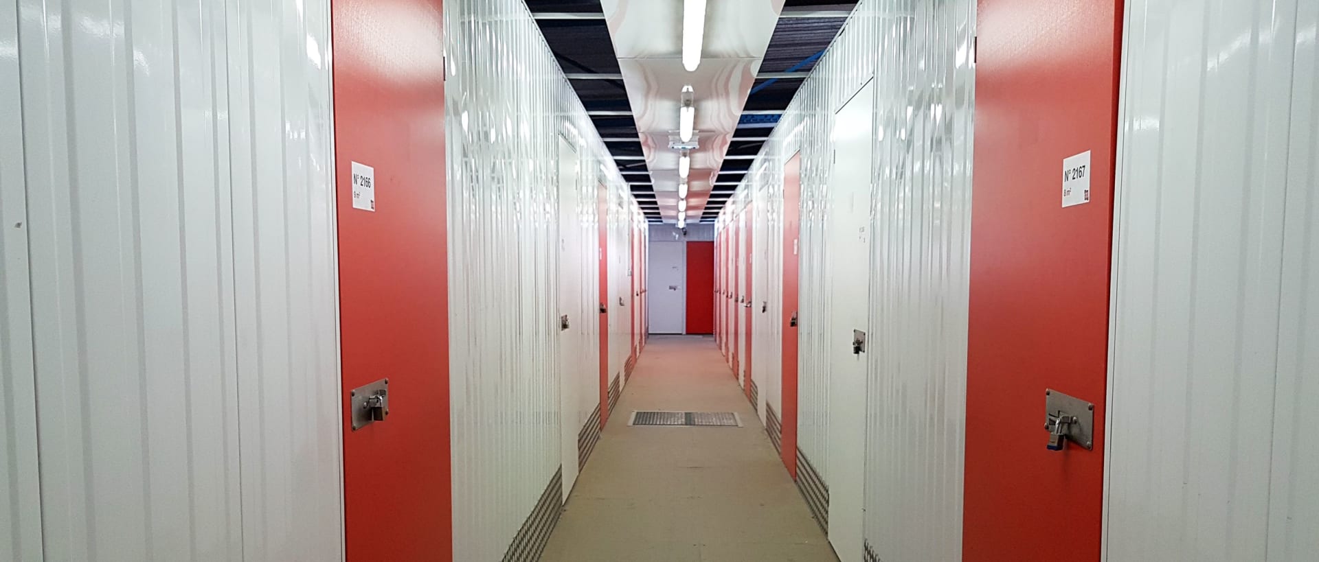 Couloir intérieur avec portes de boxes blanches et murs rouges du centre HOMEBOX Le Havre