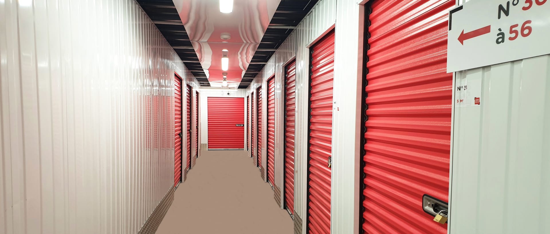 Couloir intérieur avec rangées de portes de boxes rouges du centre HOMEBOX Les Pennes-Mirabeau