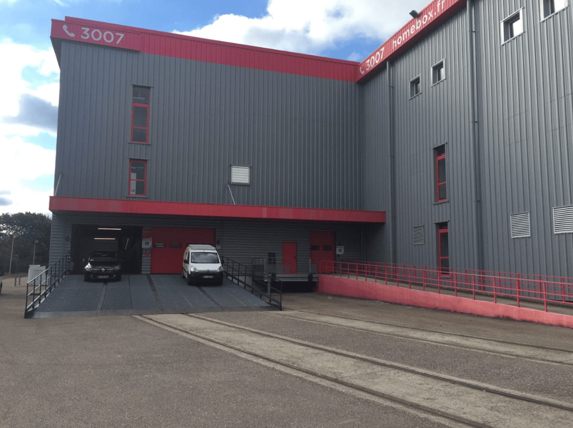 Arrière du bâtiment gris avec accès logistique et signalétique rouge, HOMEBOX Metz, 37 avenue des Deux Fontaines à Metz