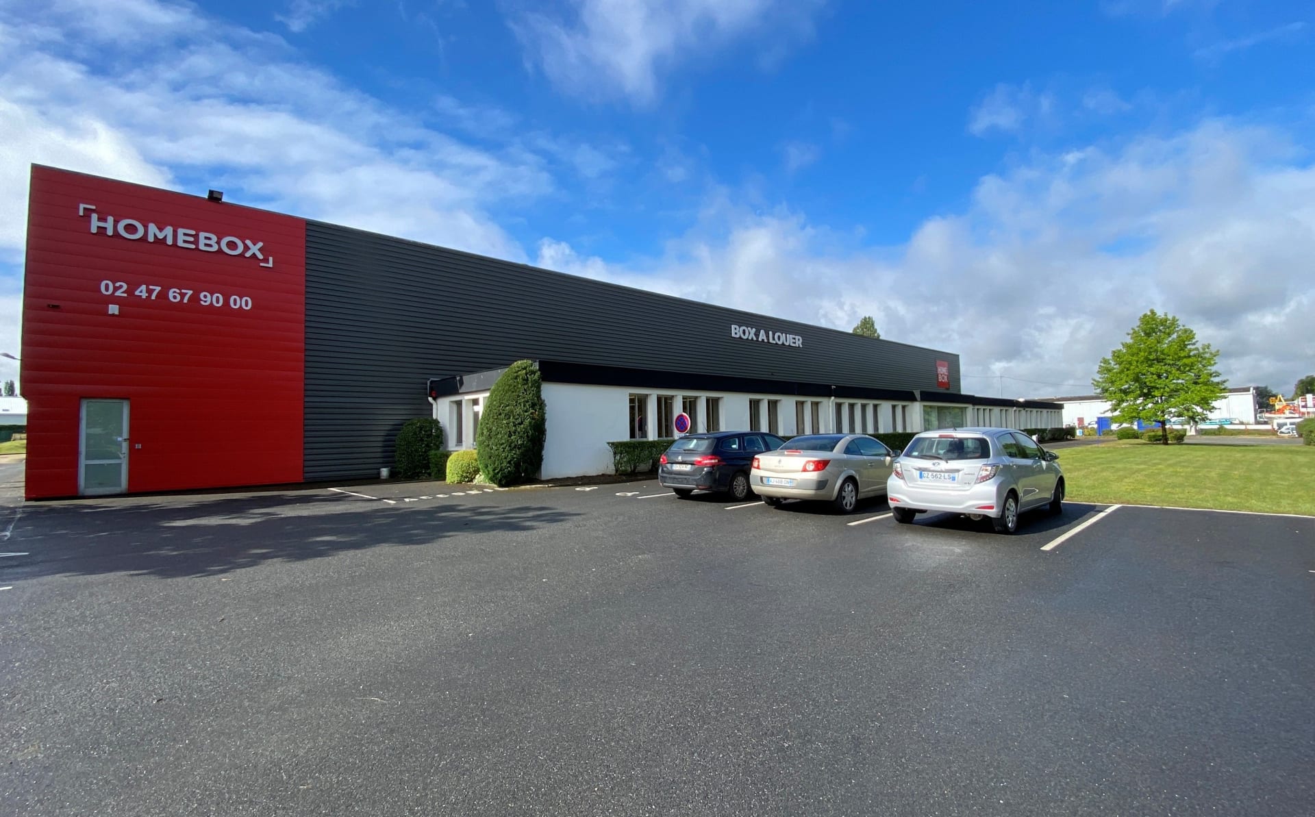Façade noire et rouge avec enseigne et parking sous ciel bleu, HOMEBOX Tours, 9 rue Joseph Cugnot à Joué-les-Tours