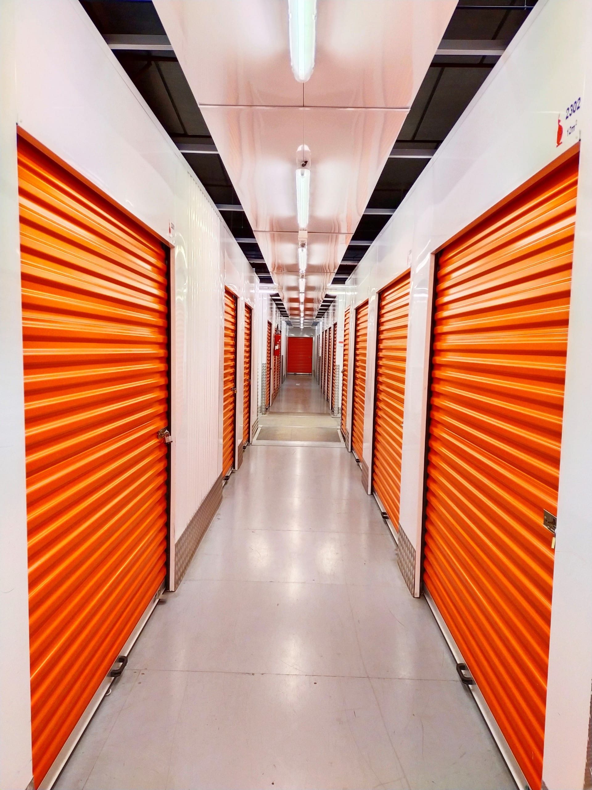 Couloir avec longues rangées de portes orange et éclairage central du centre HOMEBOX Maurepas