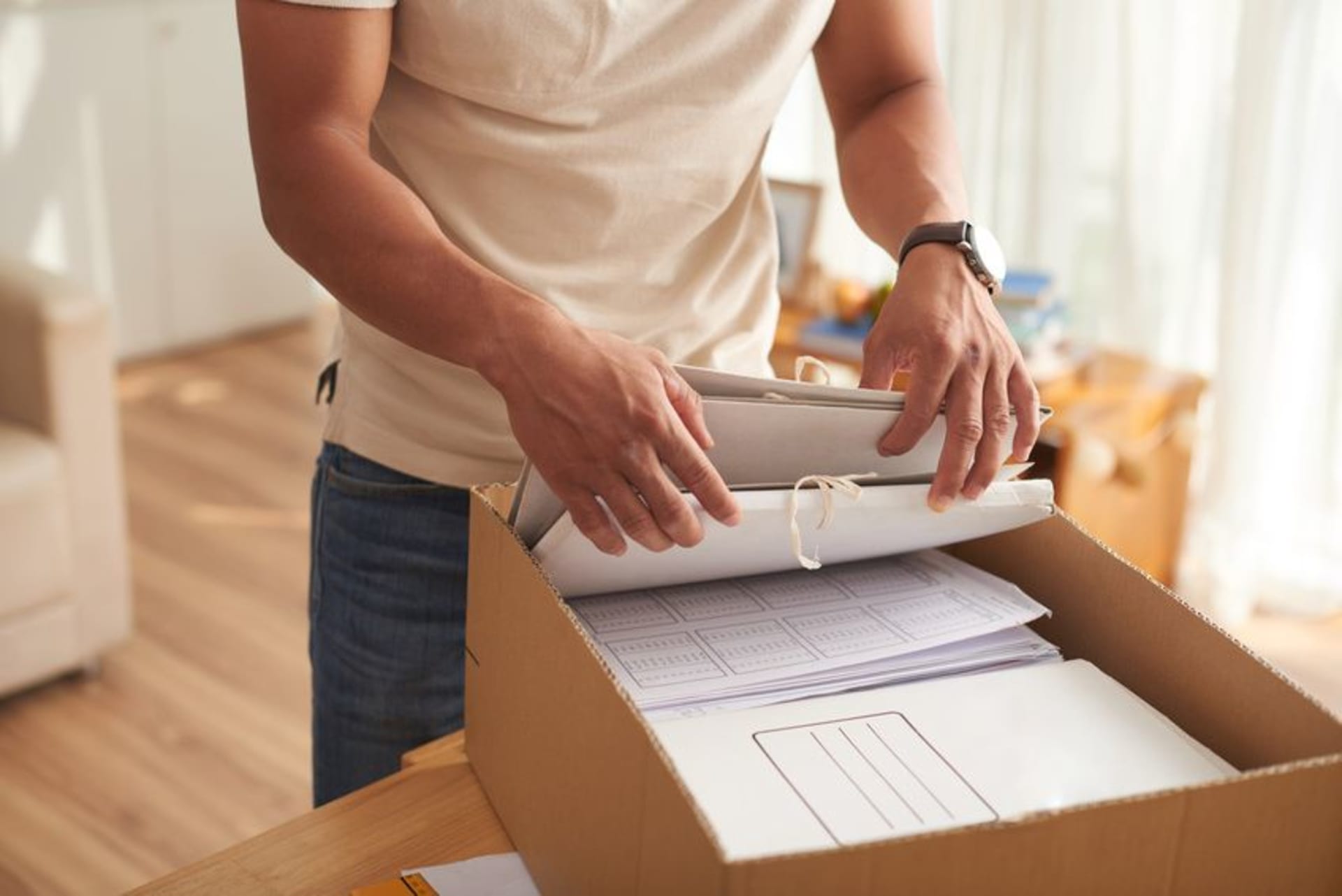 Homme rangeant des dossiers de documents dans un carton de déménagement