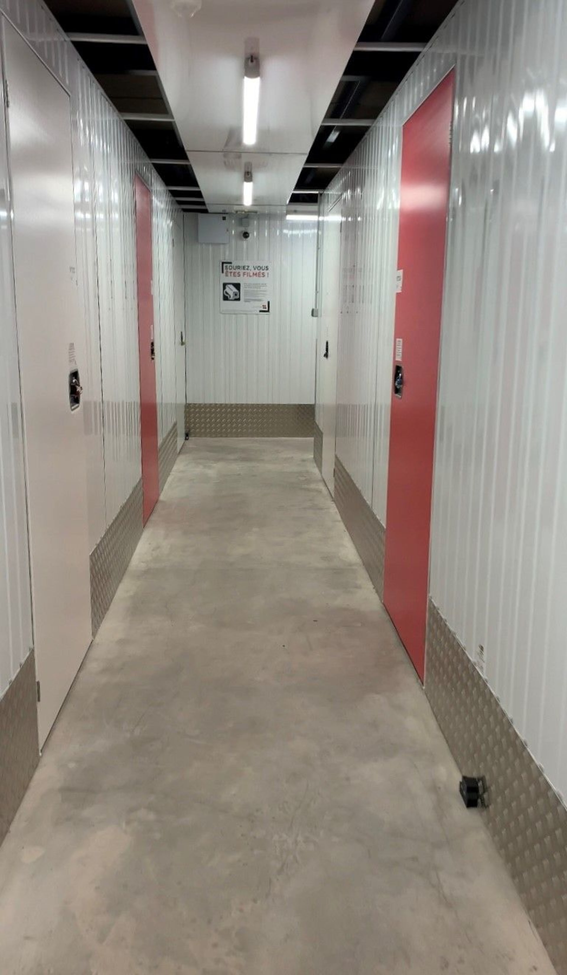 Couloir lumineux desservant les box de stockage aux portes rouges du centre HOMEBOX Montpellier