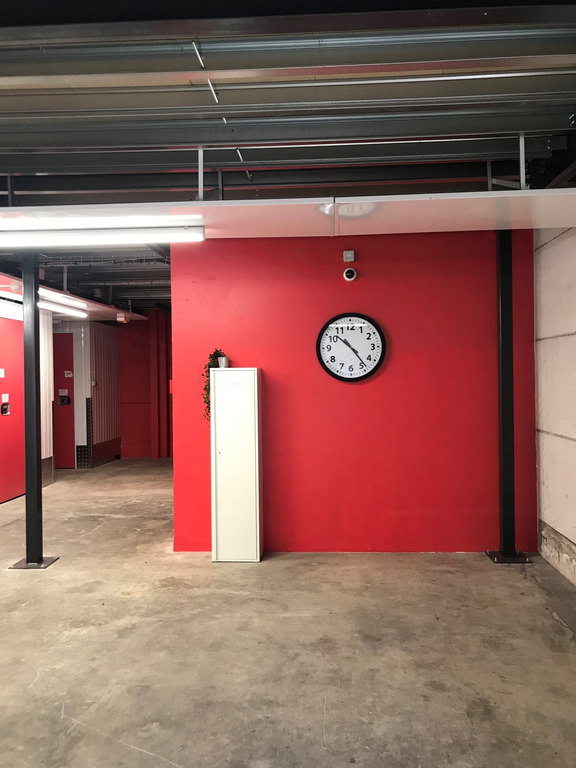Zone de déchargement intérieure avec horloge murale sur fond rouge du centre HOMEBOX Montpellier