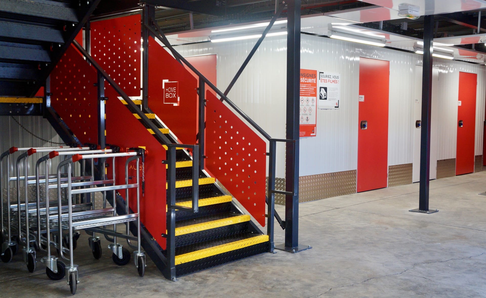 Zone de déchargement avec escalier rouge, chariots de manutention et portes de box du centre HOMEBOX Montpellier