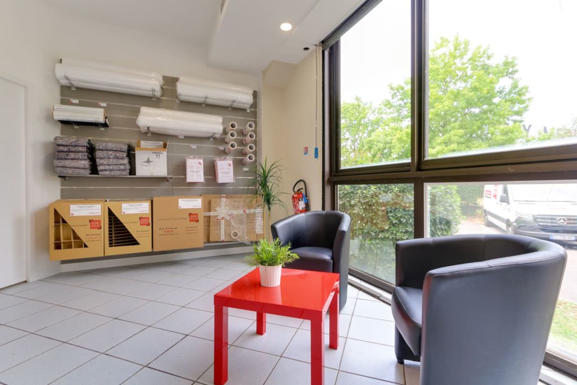 Espace boutique avec fournitures de déménagement, fauteuils et table rouge du centre HOMEBOX Boissy-Saint-Léger