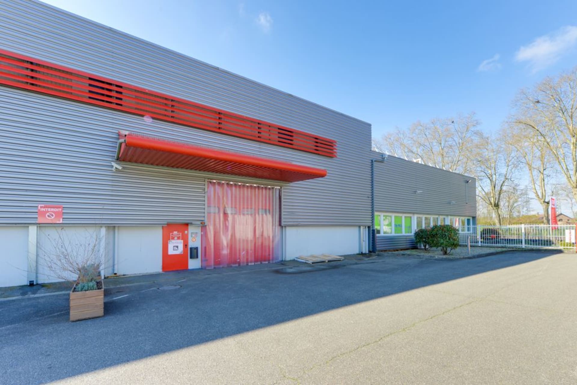 Quai de chargement extérieur avec auvent rouge, lanières plastiques et accès véhicules, HOMEBOX Strasbourg, 8 rue du Doubs à Strasbourg