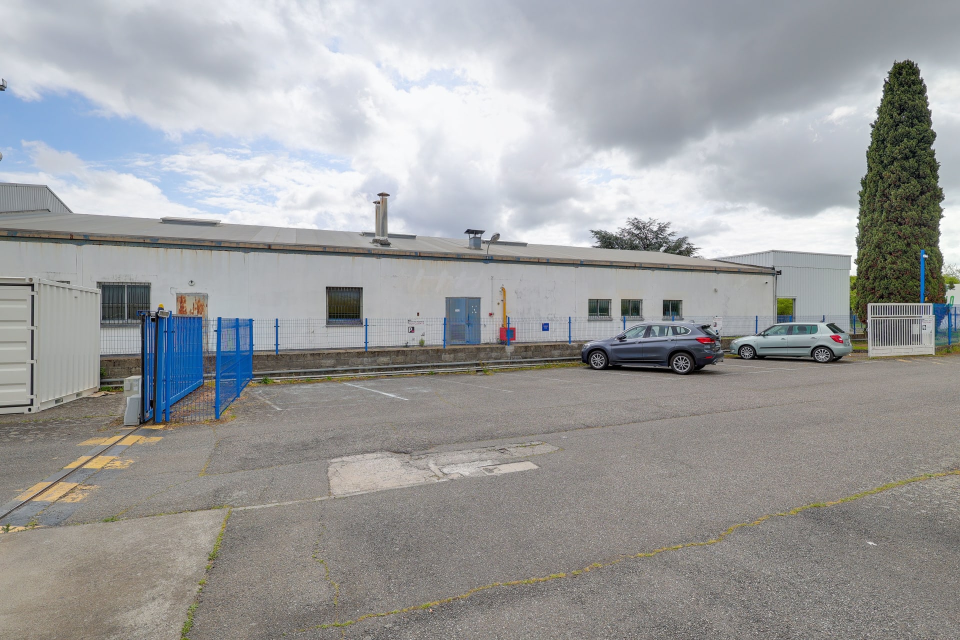 Bâtiment blanc de stockage et places de parking devant la clôture bleue, HOMEBOX Toulouse Babinet, 14 rue Jacques Babinet à Toulouse