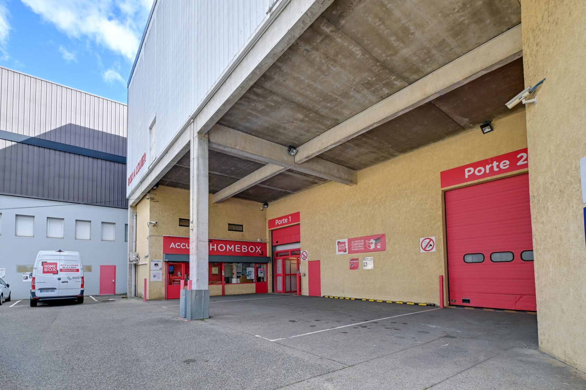 Cour intérieure avec accueil, portes de chargement rouges et camionnette stationnée, HOMEBOX Lyon Ouest, 17 rue des Rosieristes à Champagne au Mont d'Or