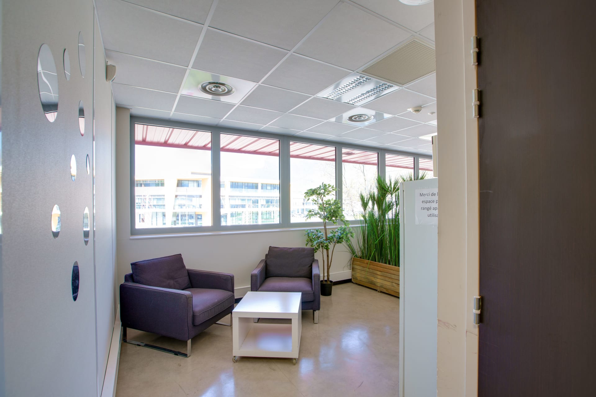 Espace détente du centre HOMEBOX Grenoble avec fauteuils, table basse et plantes vertes.