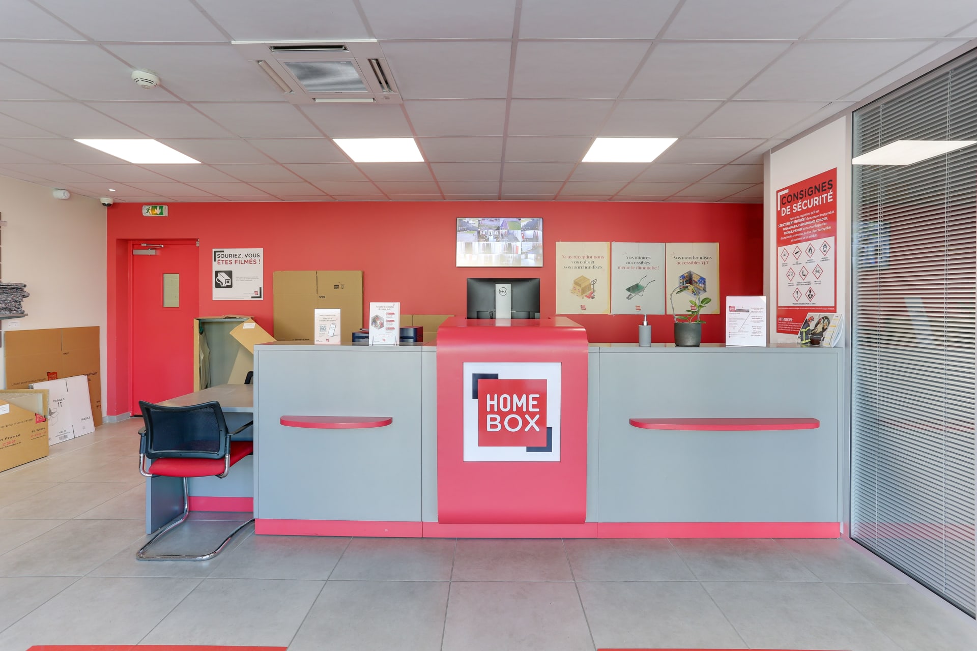 Comptoir d'accueil rose avec écran de contrôle et affiches de consignes du centre HOMEBOX Laval
