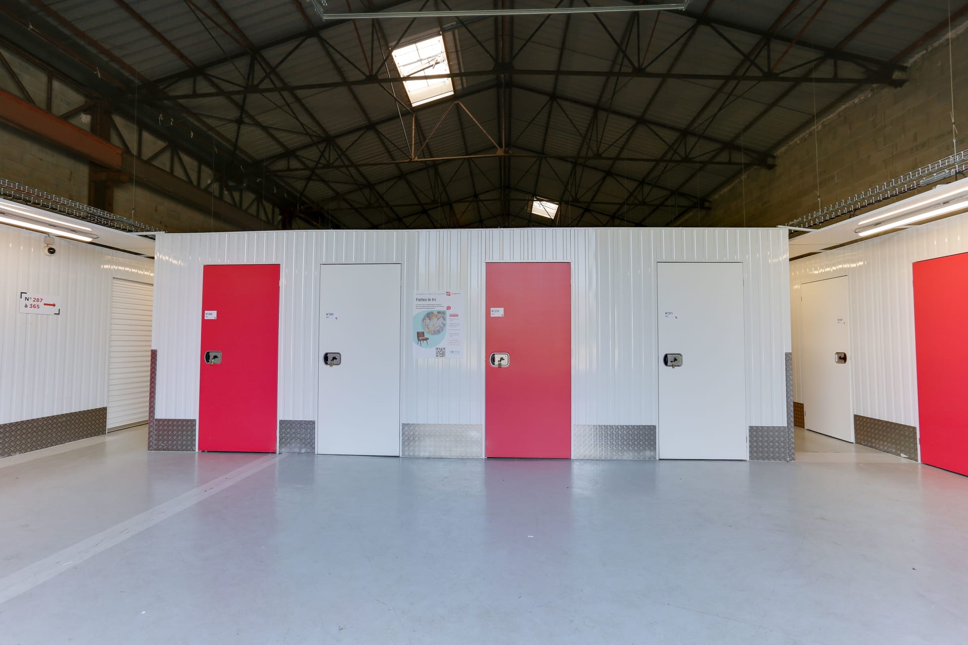 Alignement de portes de box rouges et blanches sous charpente métallique du centre HOMEBOX Laval