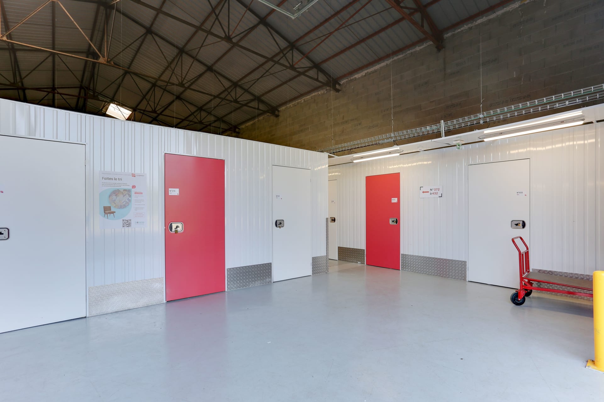 Couloir intérieur avec box rouges, blanches et chariot de manutention du centre HOMEBOX Laval