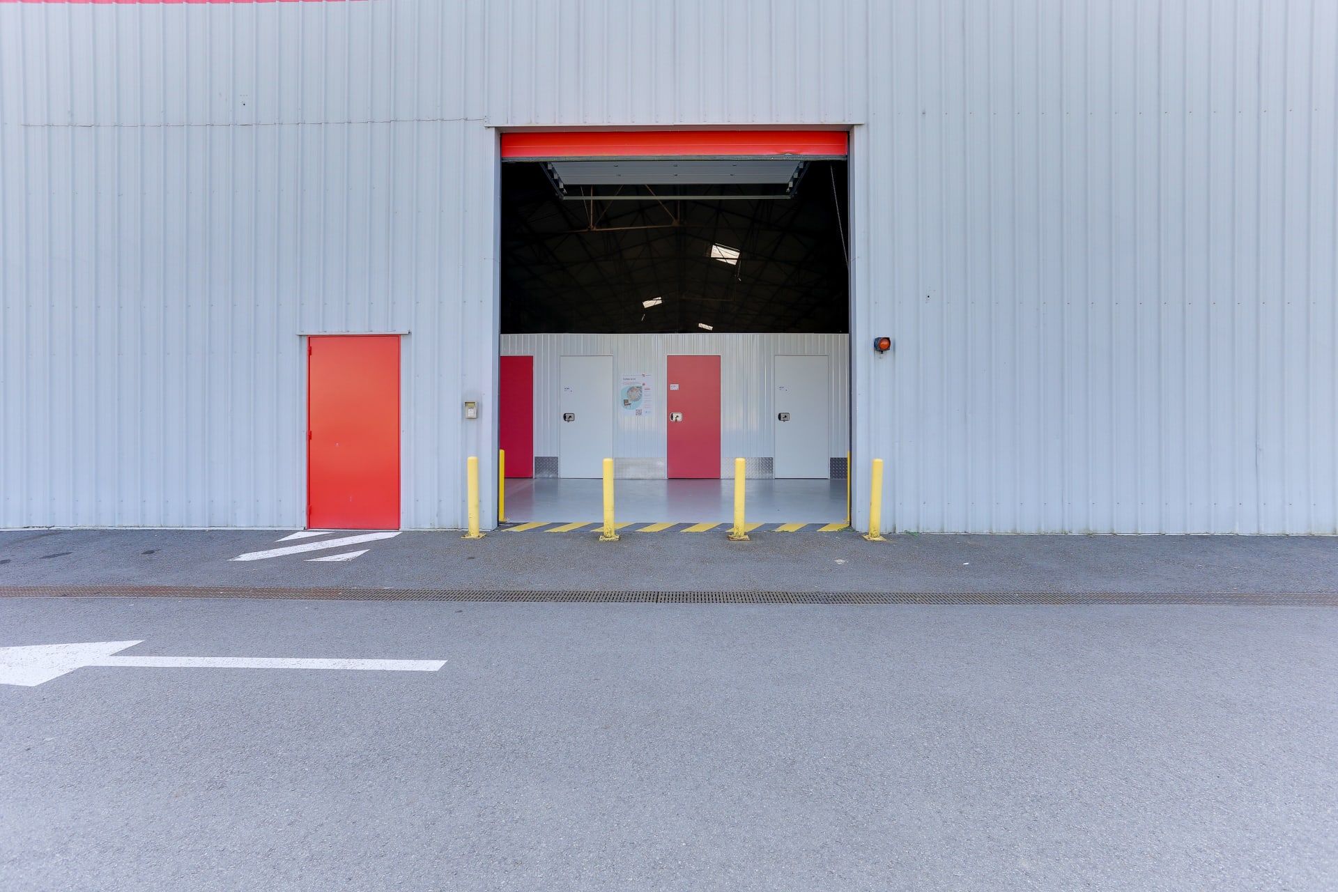 Sas d'accès véhicule ouvert avec bornes jaunes et portes de box rouges du centre HOMEBOX Laval