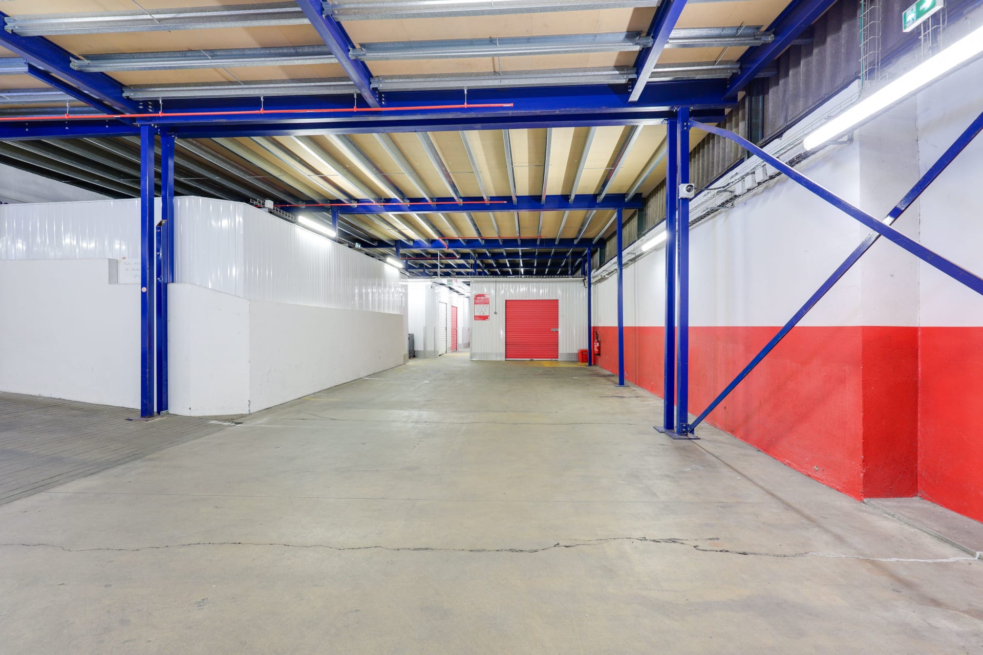 Zone de chargement intérieure avec structure métallique bleue et porte de box rouge du centre HOMEBOX Quimper Gare