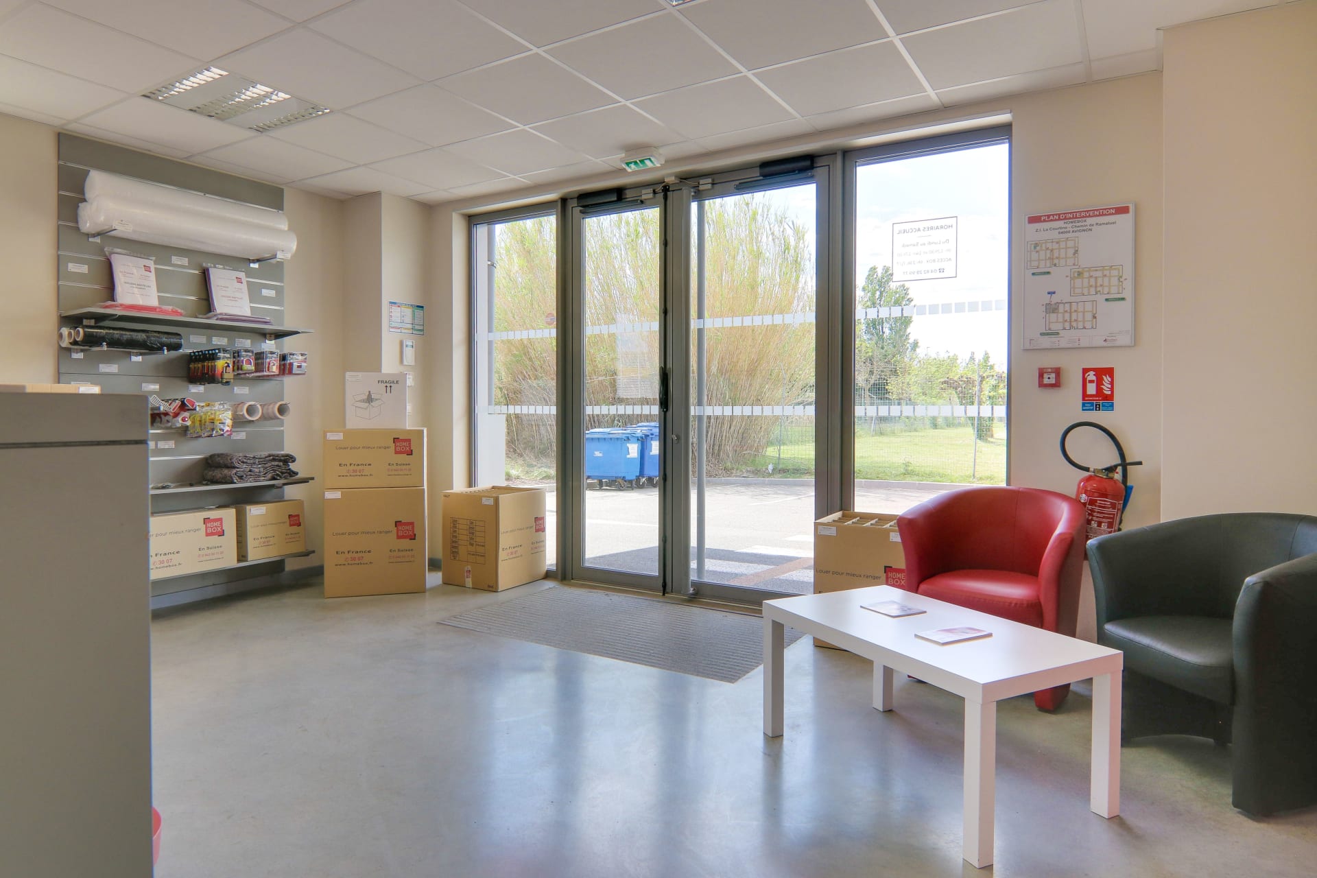 Espace d’accueil du centre HOMEBOX Avignon avec fauteuils, table basse et cartons.
