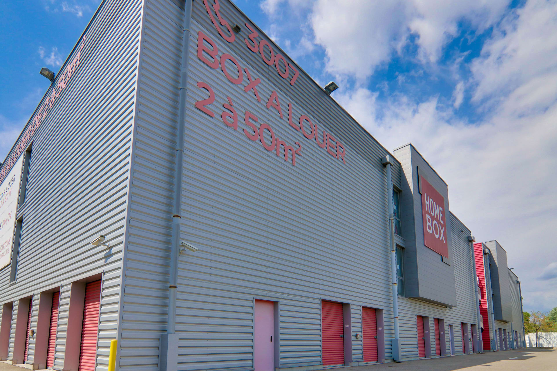 Vue latérale du centre HOMEBOX Avignon avec portes de box rouges et inscriptions murales.
