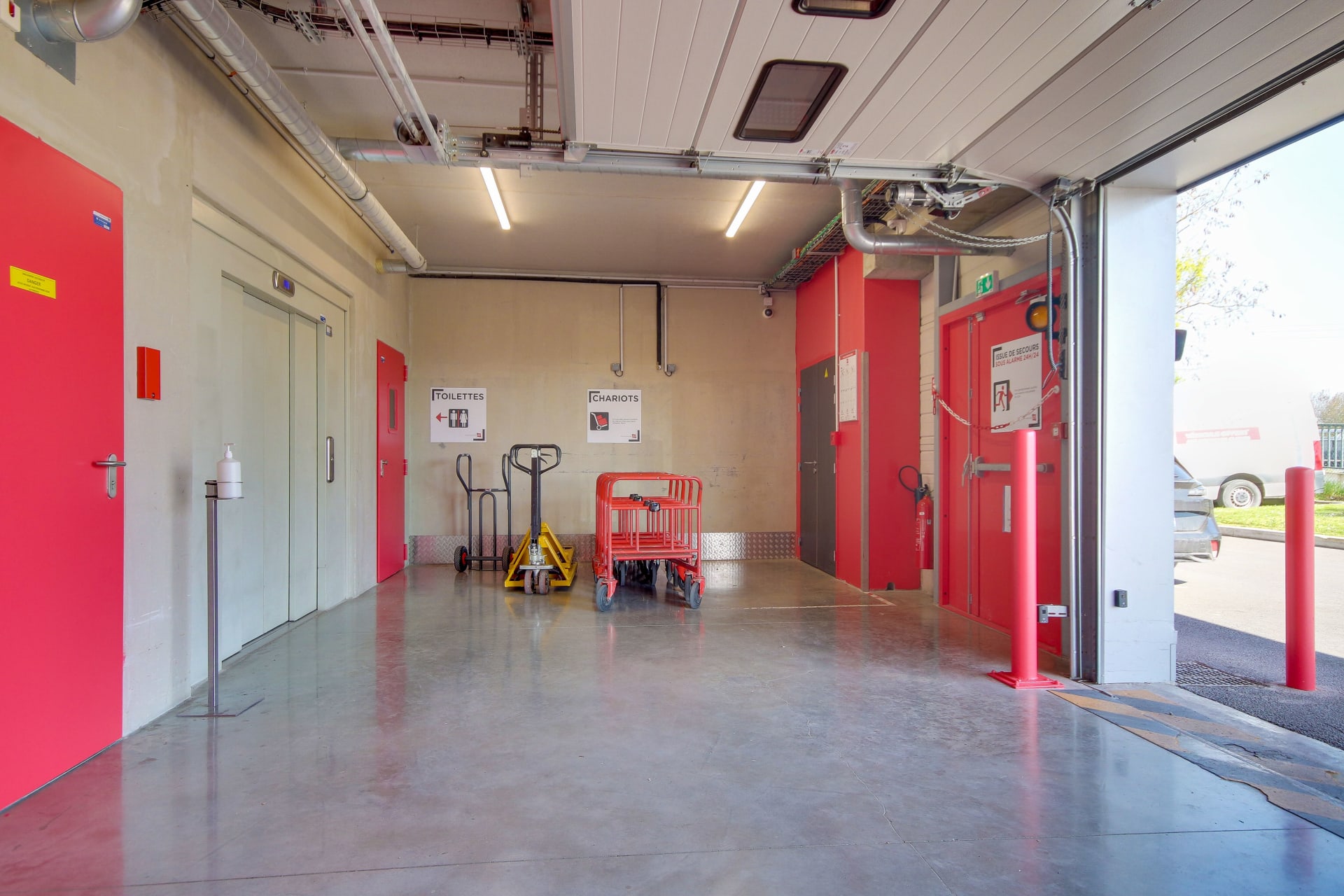 Zone de manutention avec chariots, portes coupe-feu roses et accès véhicule du centre HOMEBOX Reims Nord