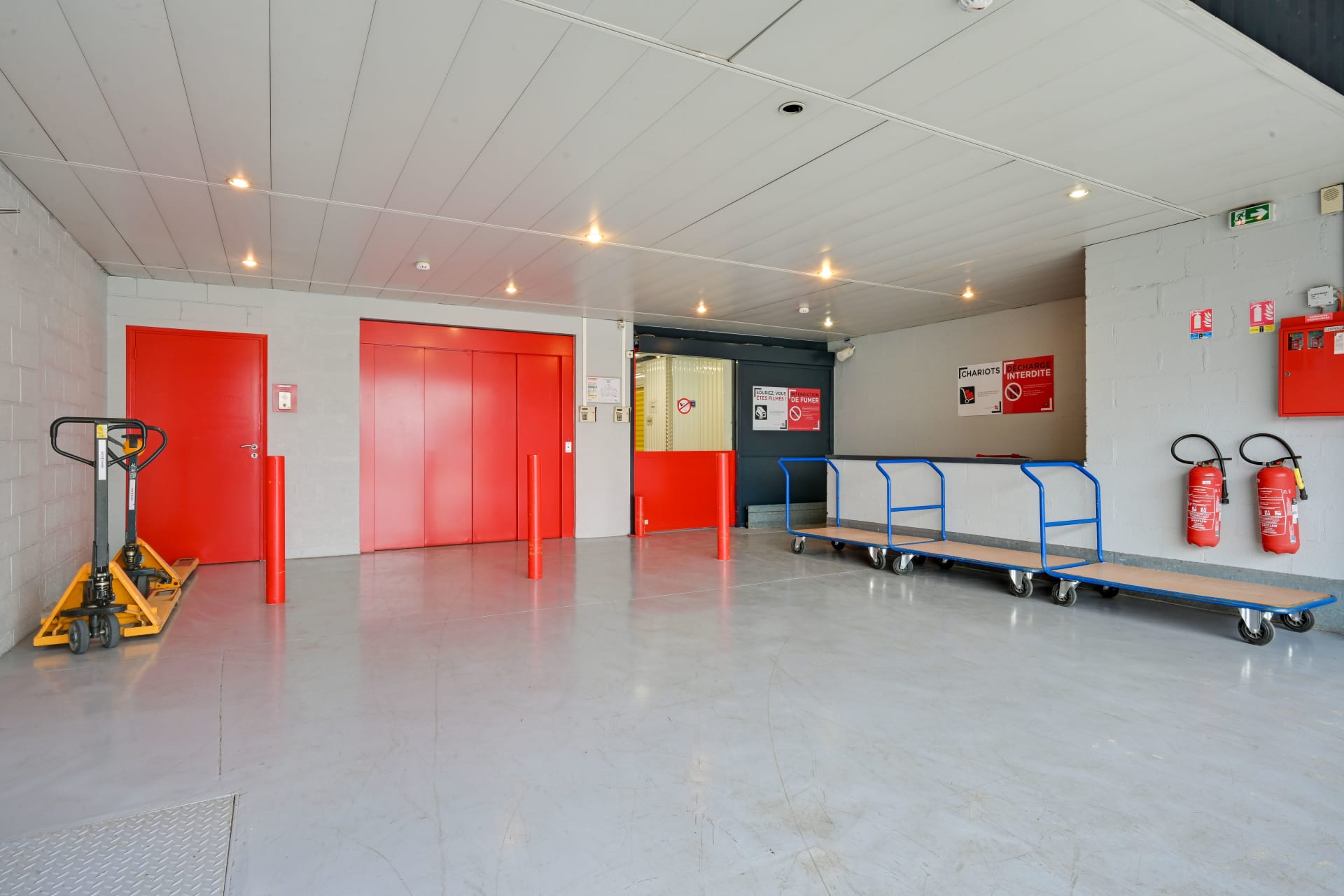 Hall intérieur avec monte-charge rouge, chariots de manutention et extincteurs du centre HOMEBOX Plaisir