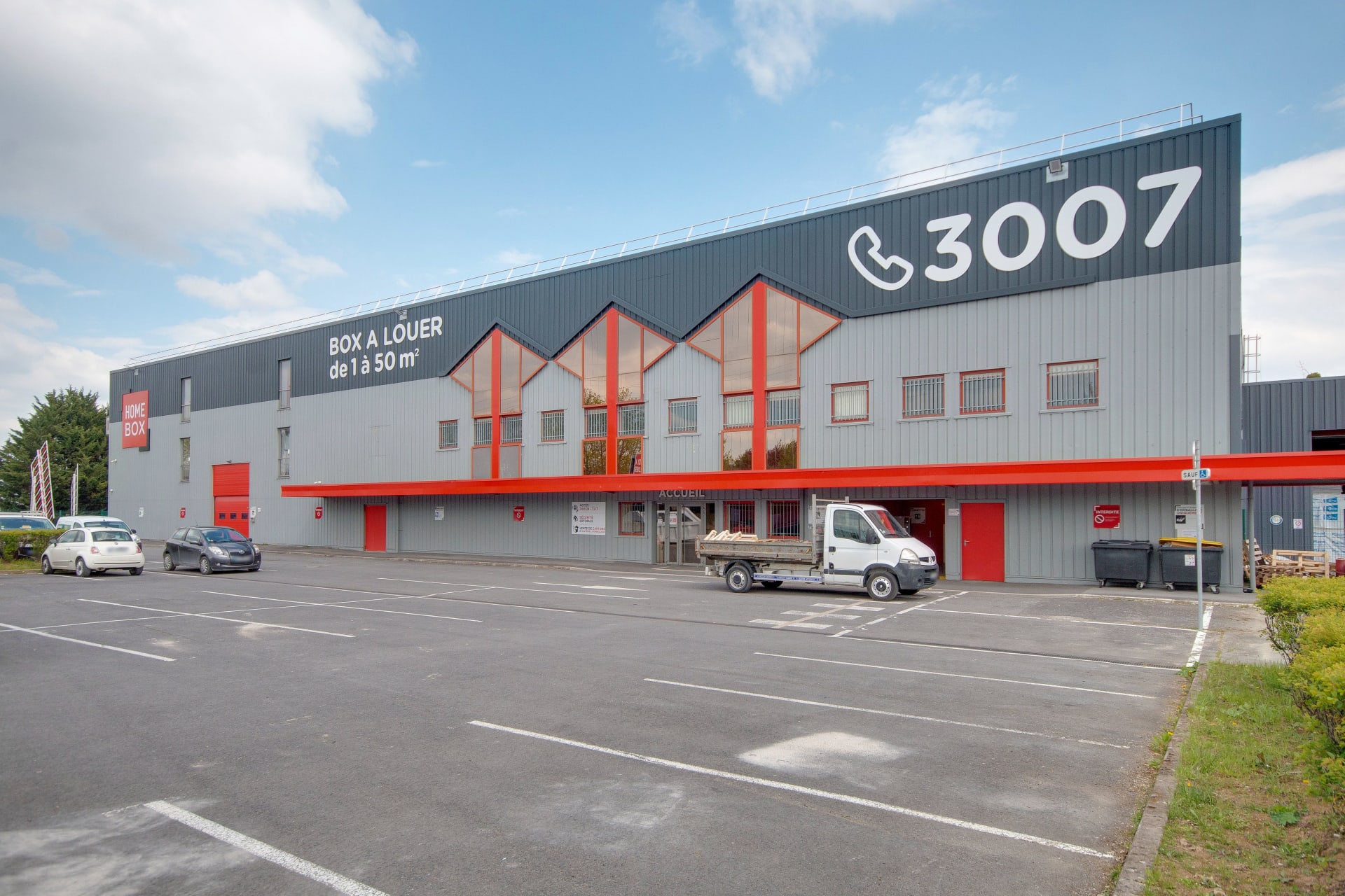 Longue façade industrielle grise avec marquage Box à louer et parking devant, HOMEBOX Reims Sud, Rue William Shakespeare à Reims