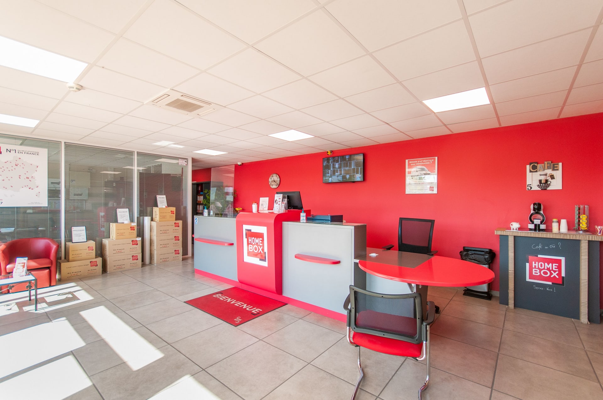 Espace accueil rouge avec cartons et table de consultation du centre HOMEBOX Troyes