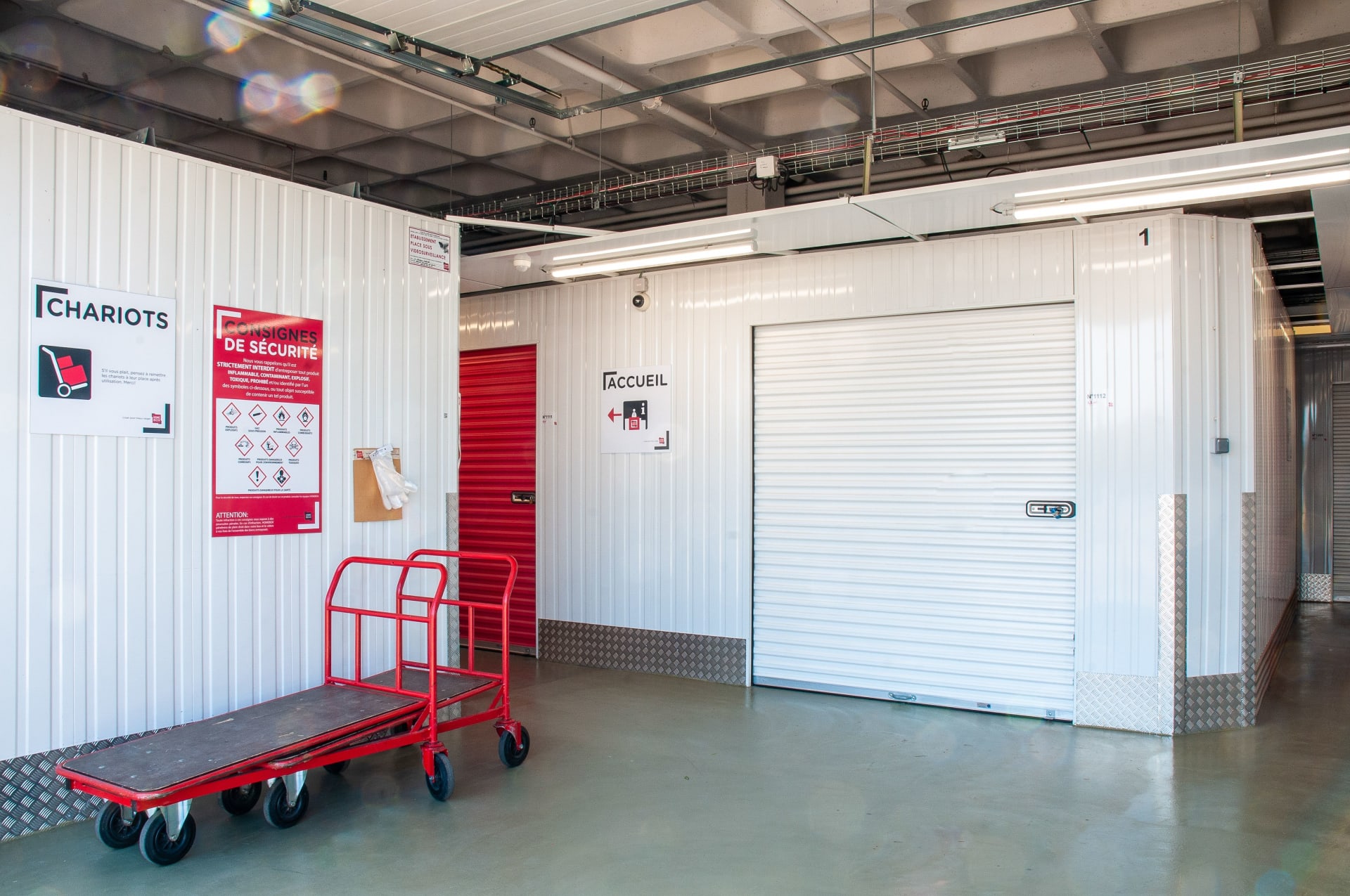 Chariot rouge devant un box de stockage avec pictogrammes consignes du centre HOMEBOX Troyes