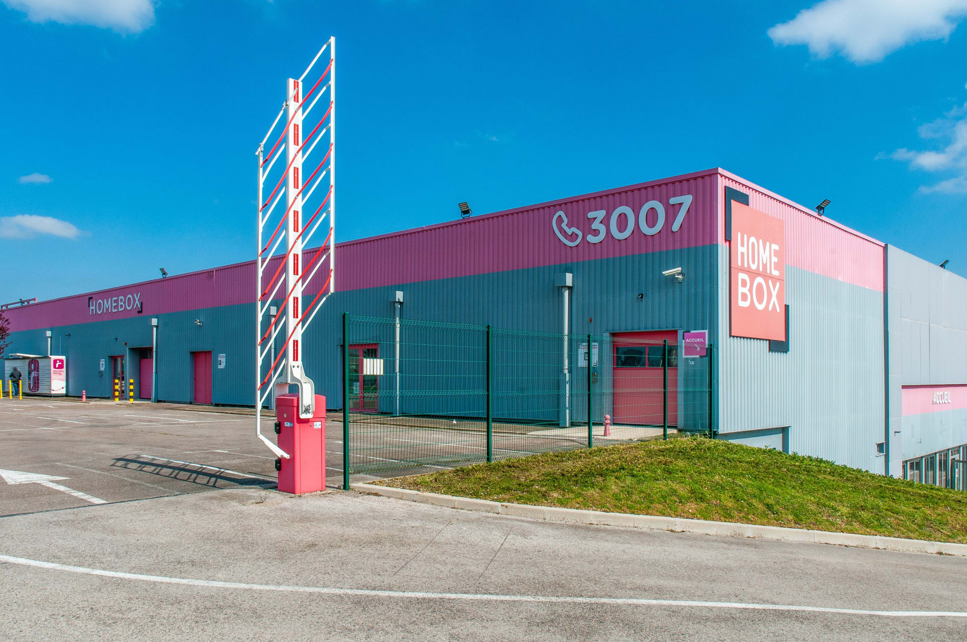 Vue d'angle de la façade rose et grise avec enseigne lumineuse, HOMEBOX Troyes, 2 à 10 rue Maryse Bastié à Barberey-Saint-Sulpice
