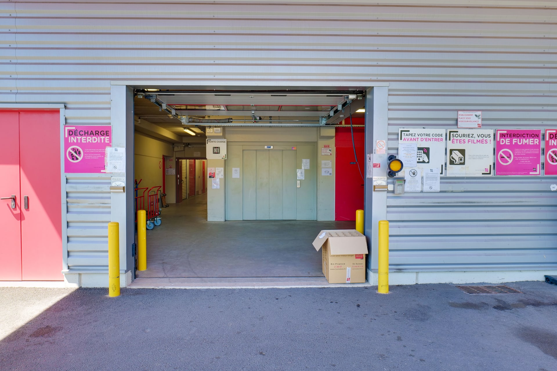 Porte de garage ouverte avec accès au couloir intérieur et affichage sécurité, HOMEBOX Limoges, 8 Allée Louis Daubenton ZAC Beaubreuil à Limoges