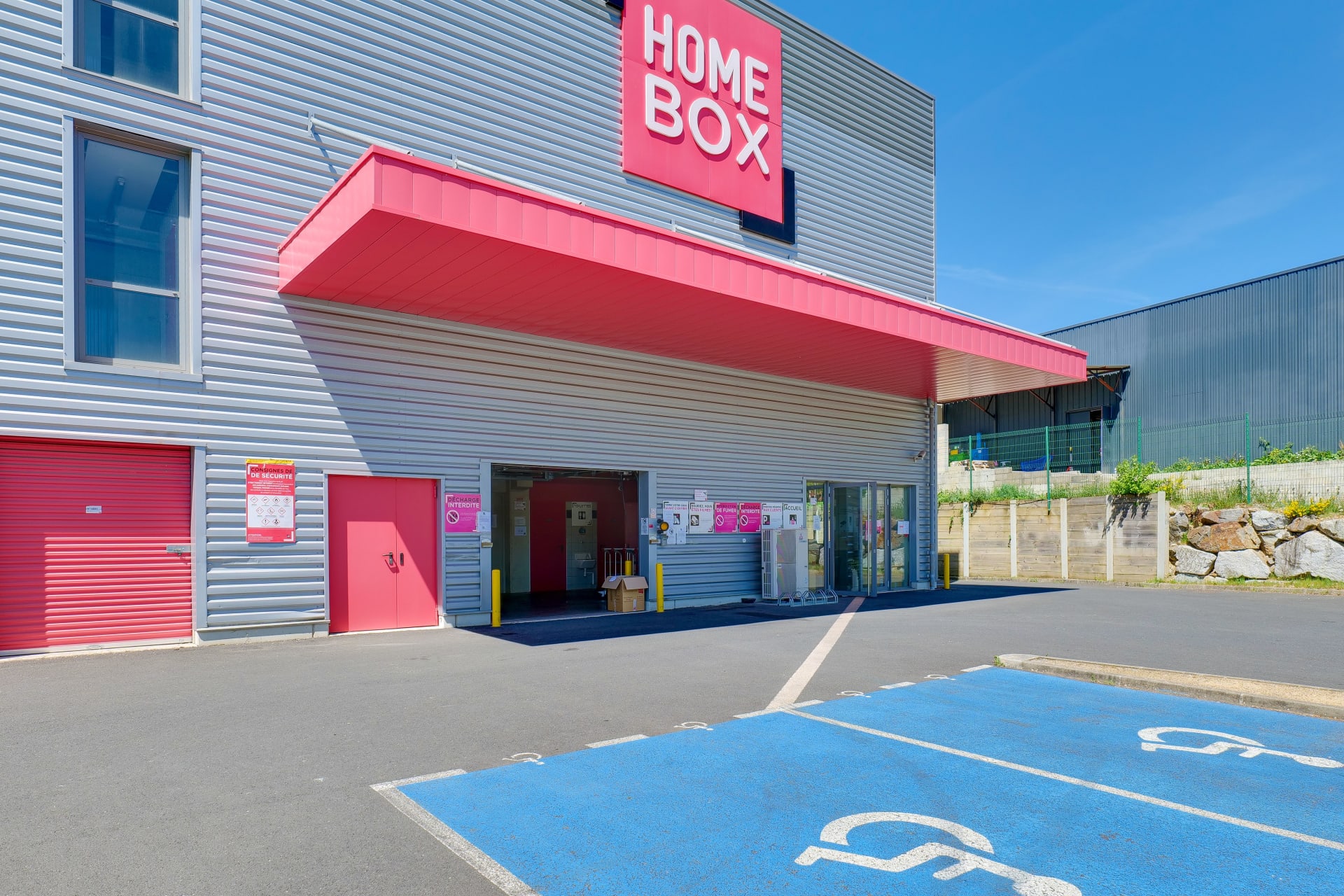 Entrée du centre avec auvent rouge et places PMR, HOMEBOX Limoges, 8 Allée Louis Daubenton ZAC Beaubreuil à Limoges
