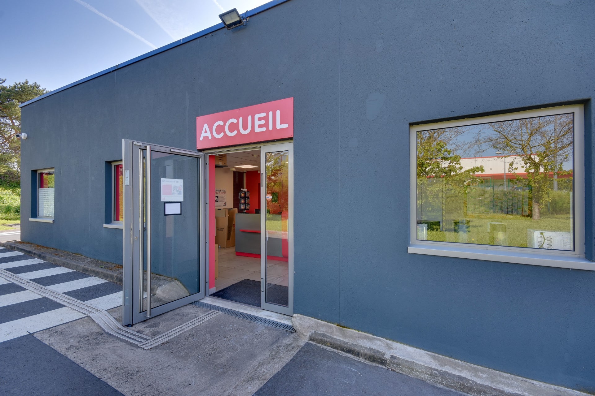 Entrée vitrée d'accueil avec enseigne rose et passage piéton, HOMEBOX Lille Lomme, Rue du Traité de Rome à Lomme