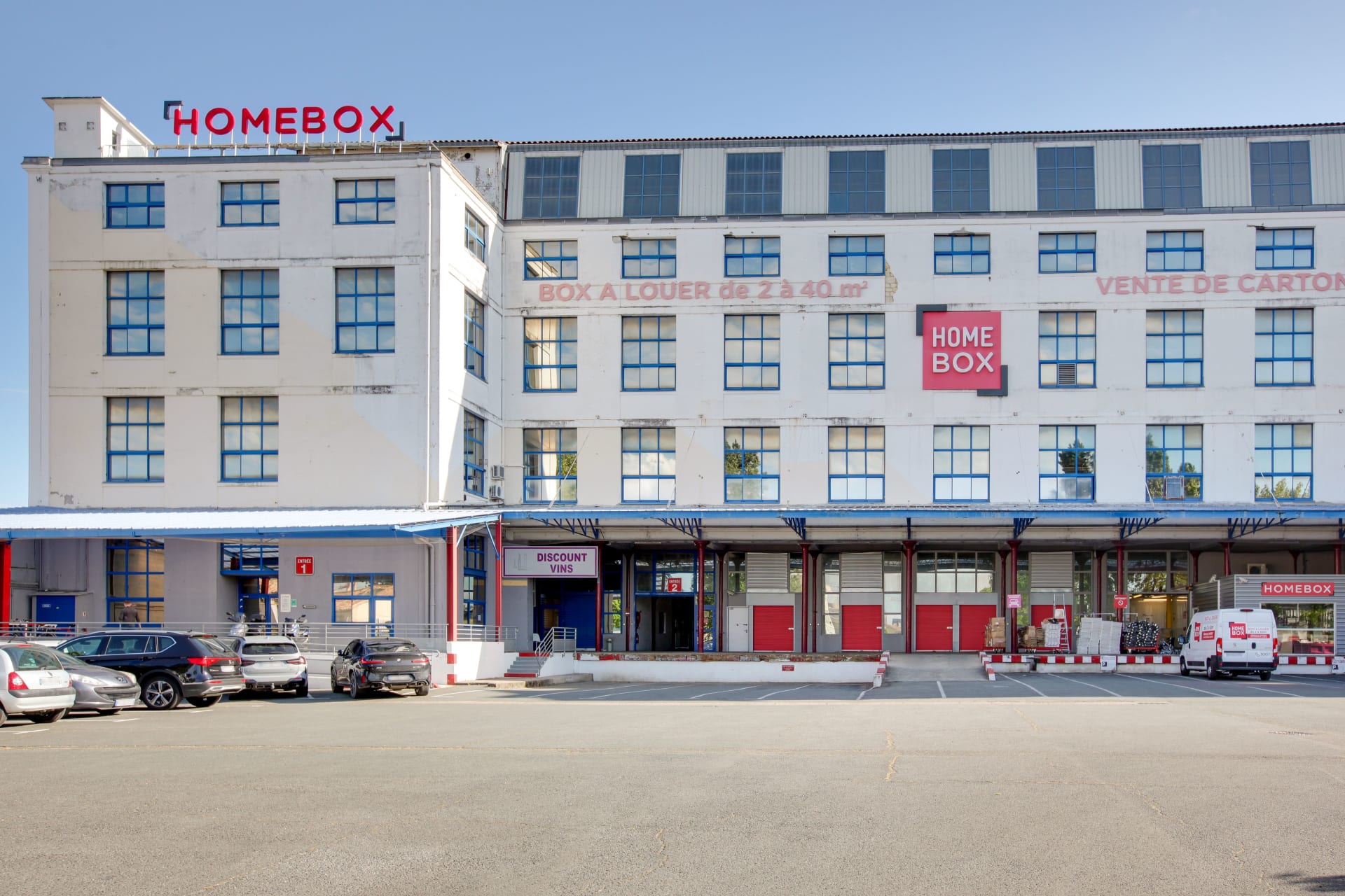 Façade industrielle blanche avec enseignes et quais de chargement, HOMEBOX Bordeaux Centre, 130 rue Achard à Bordeaux