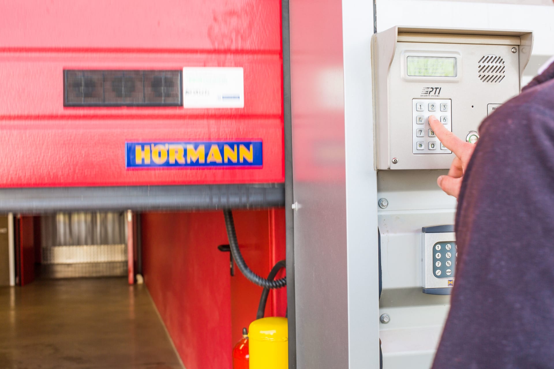 Digicode du centre HOMEBOX Albertville près d’une porte sectionnelle rouge.