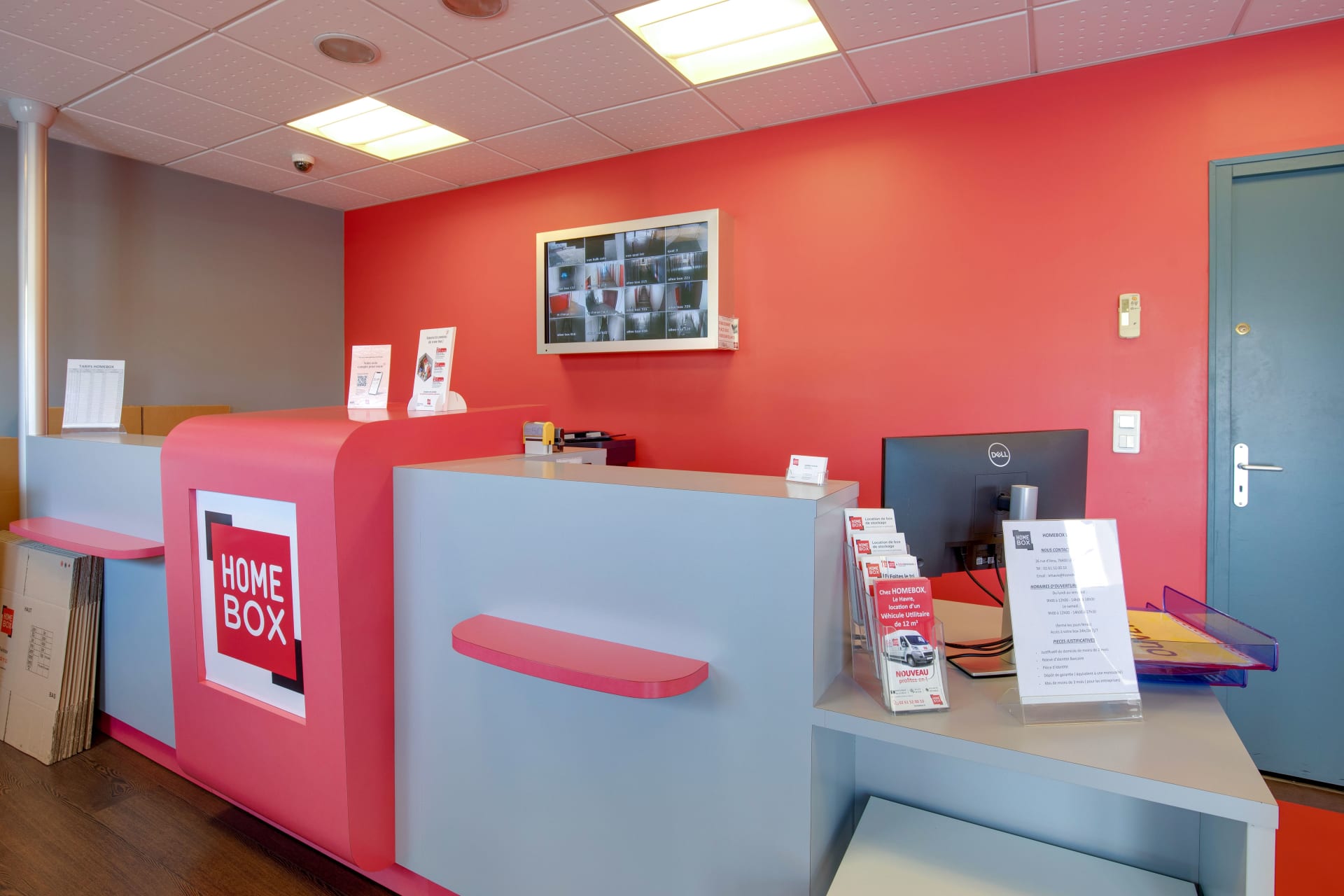 Espace d'accueil intérieur avec comptoir rose HOMEBOX et écran de vidéosurveillance du centre HOMEBOX Le Havre