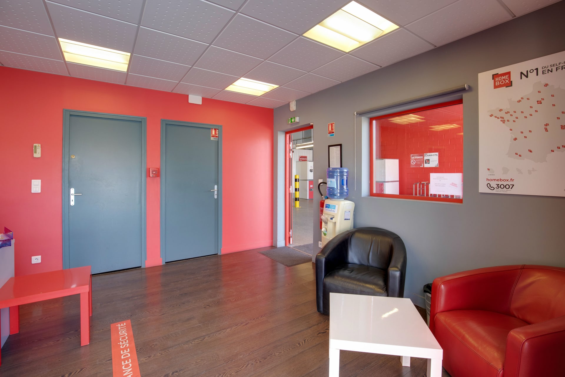 Salon d'attente intérieur avec fauteuils en cuir, fontaine à eau et carte des centres HOMEBOX du centre HOMEBOX Le Havre