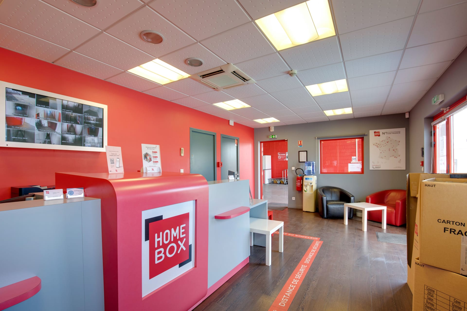 Accueil intérieur avec comptoir, fauteuils en cuir noir et rouge et carte de France HOMEBOX du centre HOMEBOX Le Havre