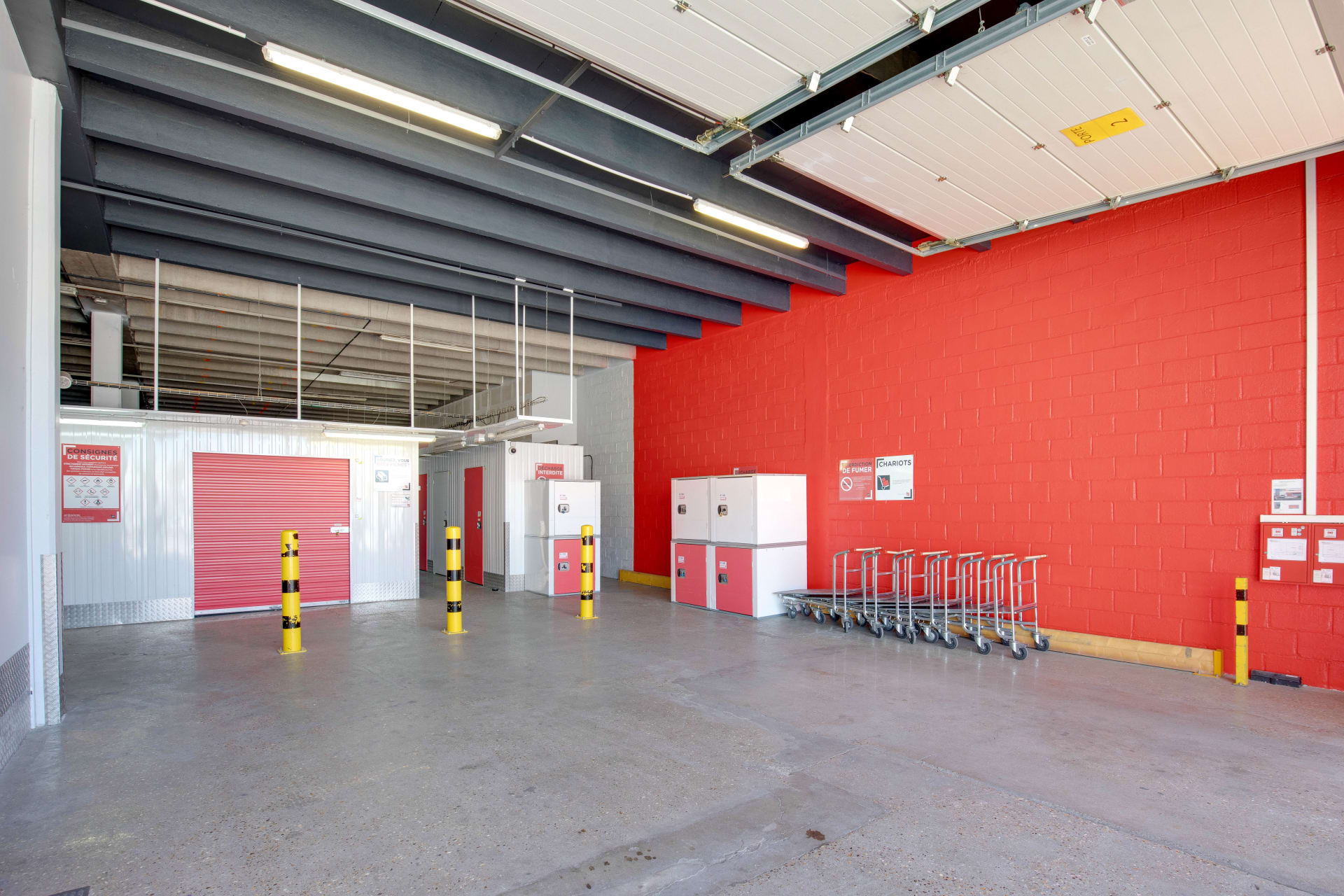 Espace de chargement intérieur avec mur rouge, alignement de chariots et porte de box rouge du centre HOMEBOX Le Havre