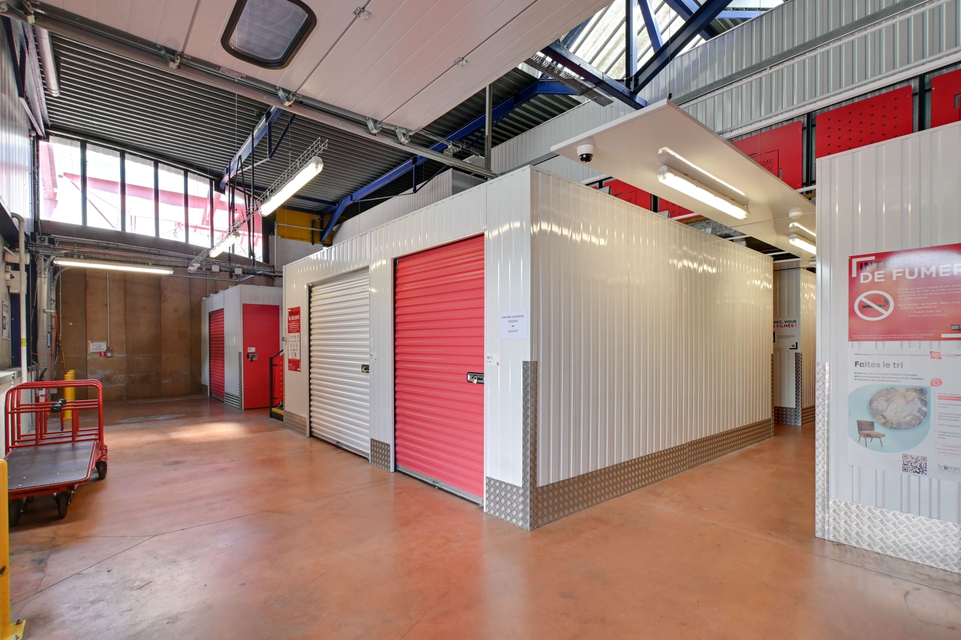 Hall intérieur avec boxes blancs et rouges, chariot et panneau d'information sécurité du centre HOMEBOX Toulon - La Farlède